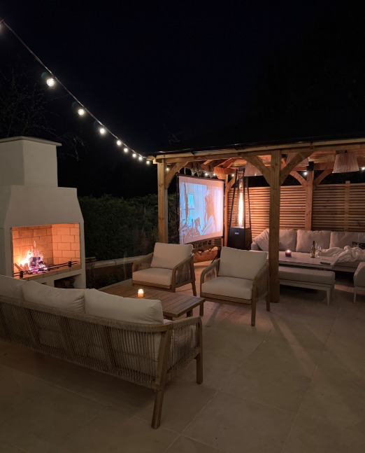 Danielle's garden terrace at night with fire pit and outdoor cinema